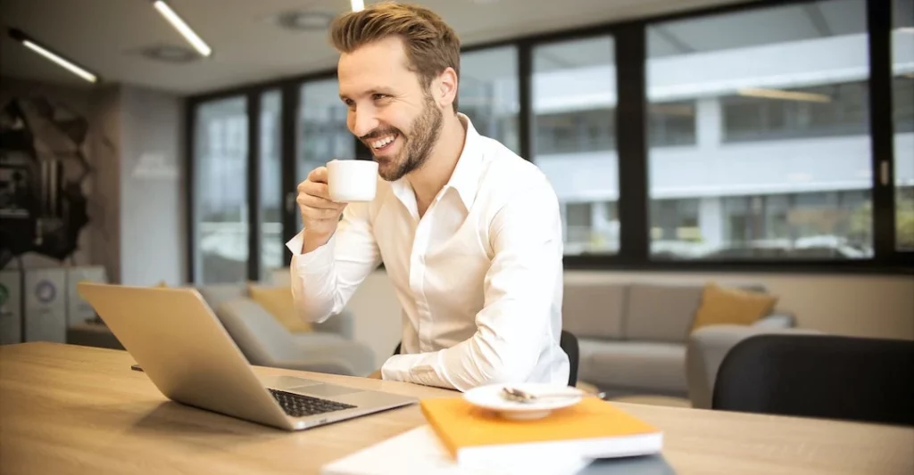 Smiling male recruiter on laptop at office using automated hiring tool