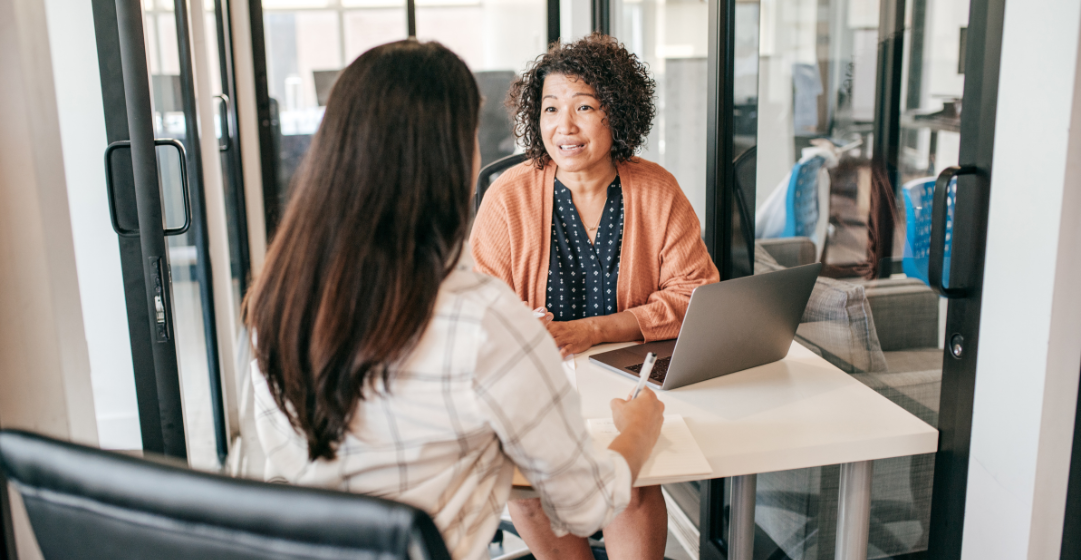 Two hiring managers reviewing candidate information during a hiring meeting.